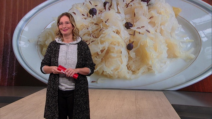 Yvonne Willicks  steht im Servicezeit-Studio. Im Hintergrund sieht man ein Bild von einer Portion Sauerkraut.