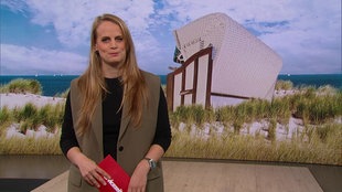 Svenja Kellershohn ist im Servicezeit-Studio. Im Hintergrund sieht man ein Bild von einem Strand.