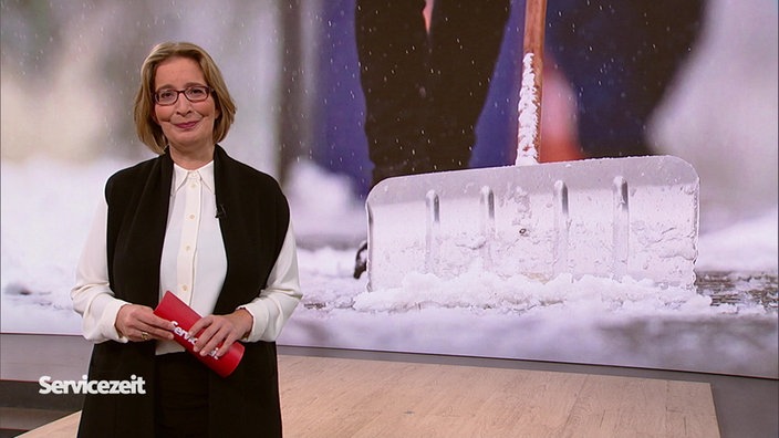 die Moderatorin steht im Studio, im Hintergrund ist eine Schneeschaufel zu sehen