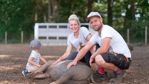 Die Protagonisten Tim und Vera streicheln ihr Schwein.