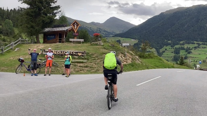 Sportliche Radfahrer auf der Straße vor einem Rastplatz mit einer Hütte