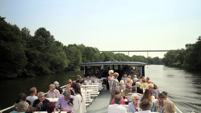 Viele Personen auf dem Ovberdeck eines Ausflugsschiffes auf einem Kanal