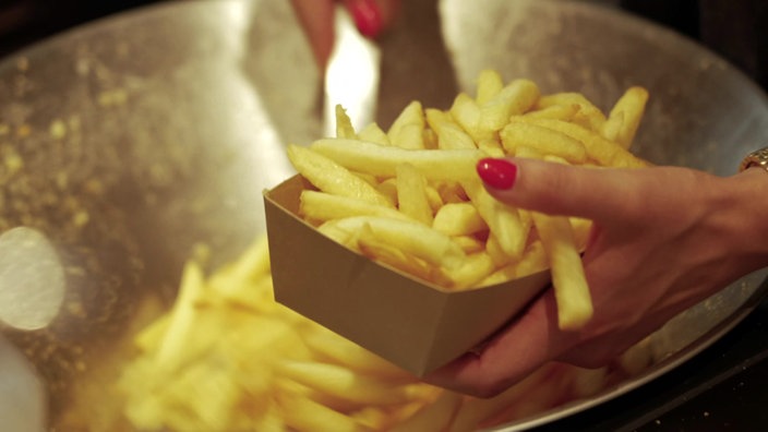 Hand hält Schale mit Pommes Frites