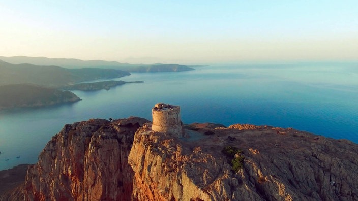 Felsiger Berggipfel mit rundem Turm hoch über dem Meer