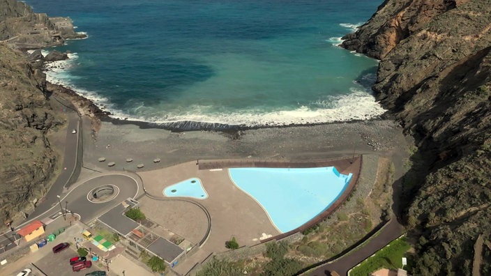 Blick von weit oben auf einen Strand mit einem Schwimmbecken