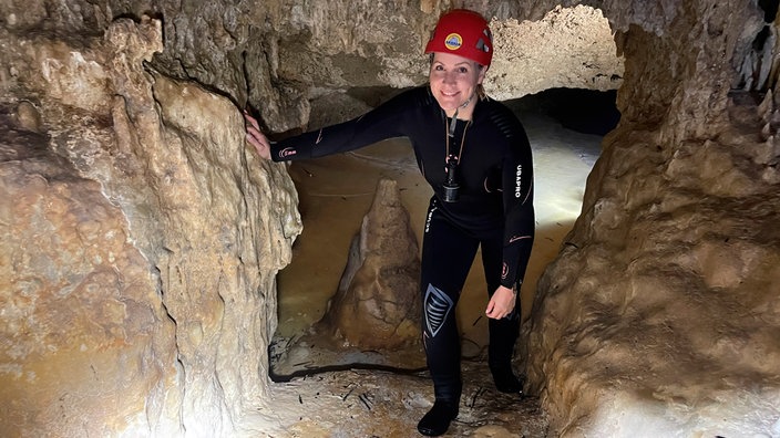 Judith Rakers mit Schutzanzug und Helm erkundet eine Höhle