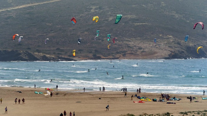 Wind- und Kitesurfer in einer Bucht mit Sandstrand