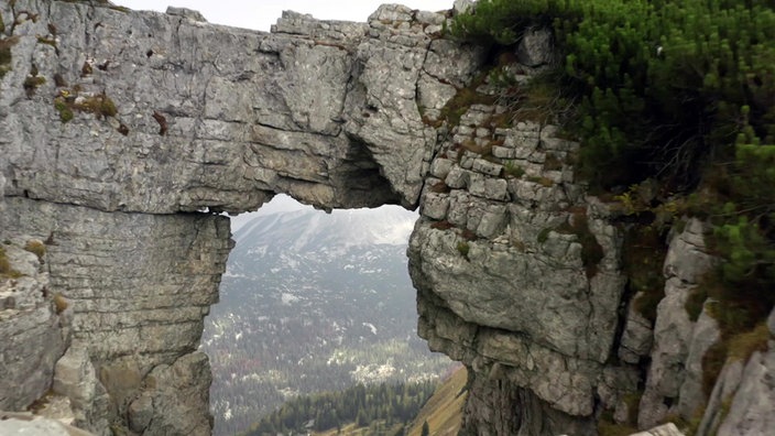 Blick durch ein Felsentor auf das Bergpanorama