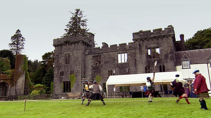 Einige Personen führen Ritterspiele vor den Ruinen von Armadale Castle auf