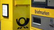 Ein Briefkasten steht neben einem Briefmarkenautomaten