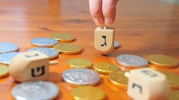 Holzdreidel und Schokoladentaler auf einem Holztisch.