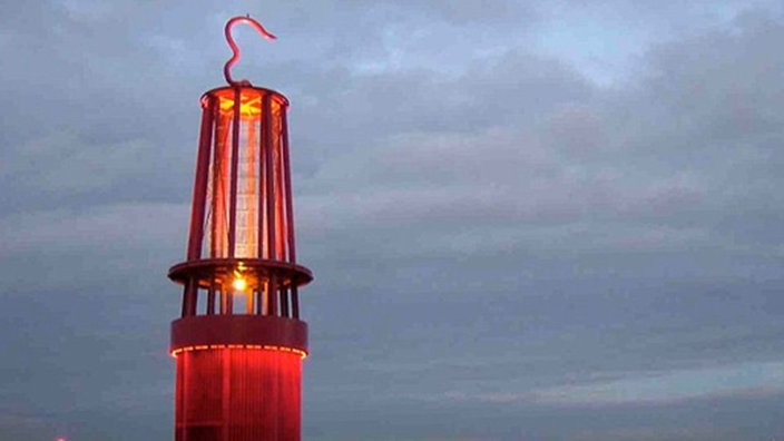 Eine riesige Grubenlampe im Vordergrund. Im Hintergrund ein bewölkter Himmel