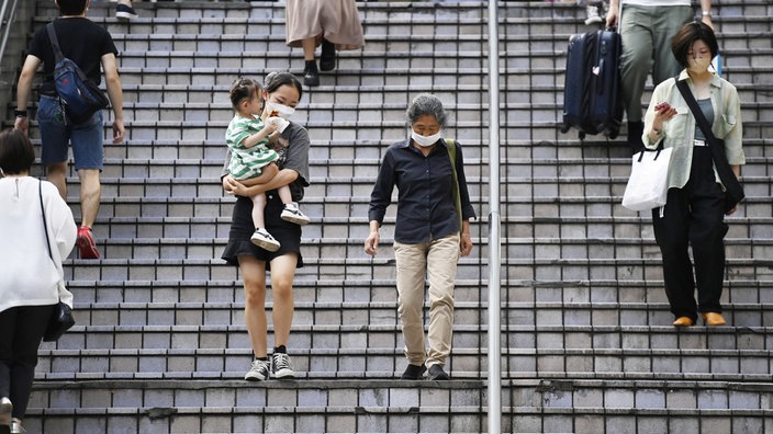 Das Beitragsbild des Dok5 "Alterndes Japan" zeigt eine junge Mutter mit Kind und eine ältere Frau im öffentlichen Raum in Tokyo, Japan 2022.