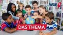 Kinder betrachten in einer Schulbibliothek gemeinsam einen Globus