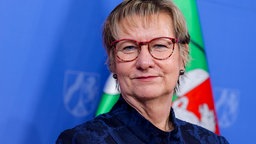 Porträtaufnahme von Sylvia Löhrmann bei einer Pressekonferenz vor einer Flagge des Landes NRW