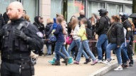 Polizei ist an einer Schule im Einsatz, Schülerinnen laufen vorbei. 