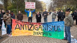 "Gemeinsam Antiziganismus bekämpfen" steht vor dem Mahnmal für Sinti und Roma in Berlin bei einer Kundgebung auf einem Banner.