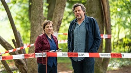 Eva Löbau und Hans-Jochen Wagner stehen bei den Dreharbeiten zu "Tatort: Ad Acta" (undatierte Filmszene) zwischen Bäumen.