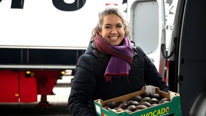 Günes Seyfarth mit einer Kiste voller Avocados in den Händen