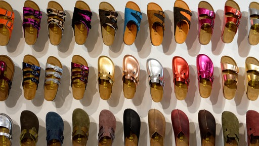 An einer Wand sind Birkenstock Schuhe ausgestellt