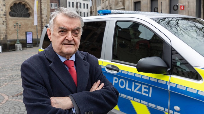 Herbert Reul neben einem Fahrzeug der Polizei auf dem Münsterplatz in Bonn (Archivbild).