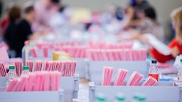 Wahlhelferinnen und Wahlhelfer öffnen bei der Auszählung der Briefwahl zur Bundestagswahl in der Messehalle 6 die rosafarbenen Umschläge.