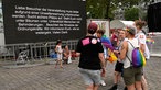 Teilnehmer beim CSD in Köln vor einer Anzeigetafel