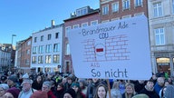 Ein Demonstrant hält ein selbstgemachtes Schild in die Luft