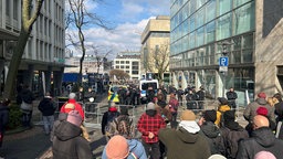 Beide Demogruppen stehen sich durch Absperrungen getrennt am Kennedyplatz gegenüber