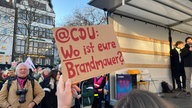 Eine Demonstrantin hält ein selbstgemachtes Schild in die Luft