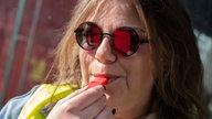 Eine Frau mit Sonnenbrille und Warnweste pustet in eine Pfeife