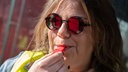 Eine Frau mit Sonnenbrille und Warnweste pustet in eine Pfeife