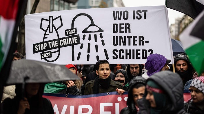 Ein Banner mit der Aufschrift "Wo ist der Unterschied?" und den Piktogrammen einer Bombe mit der Jahreszahl 2023 und einer Dusche mit der Jahreszahl 193