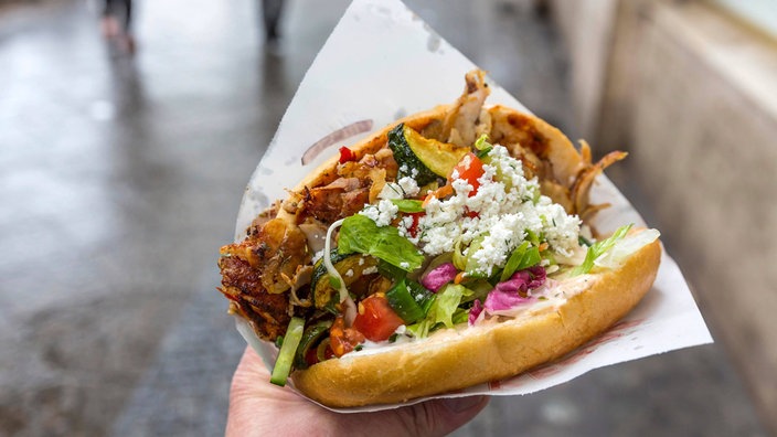 Ein Mann hält einen Döner in der Hand.