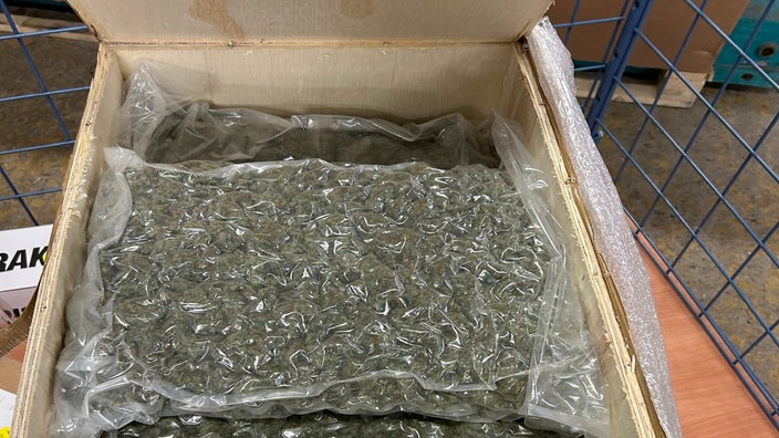 Mehrere Plastikpackungen gefüllt mit Marihuana in einer Holzkiste