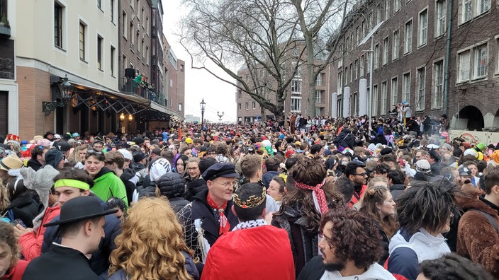 Eine Straße in Düsseldorf ist voll mit feierenden Jecken.