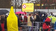 Kostümierte Personen stehen in der Nähe der Zülpicher Straße, im Hintegrund ist ein "Glaskontrolle"-Schild zu sehen.