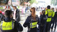 Die Polizei steht an der Haltestelle "Dasselstr./Bahnhof Süd" auf der Zülpicher Str., im Hintergrund laufen feiernde Menschen