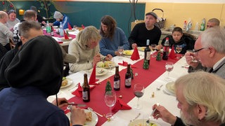 Obdachlose sitzen an einem Tisch und essen zusammen