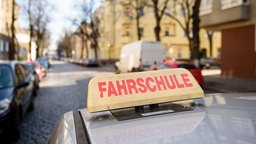 Ein Schild mit der Aufschrift "Fahrschule" ist auf dem Dach eines Fahrschulwagens montiert.