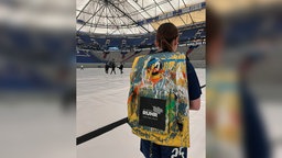 Emma mit ihrem 30 kg schweren Farbrucksack, bereit um mit ihrem Team aufs Feld zu stürmen