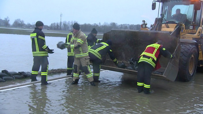 Einsatzkräfte stapeln Sandsäcke gegen Hochwasser