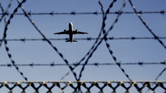 Flugzeug am Himmel, Flughafenzaun davor