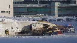 Einsatzkräfte arbeiten an umgedrehten Flugzeug auf der Startbahn