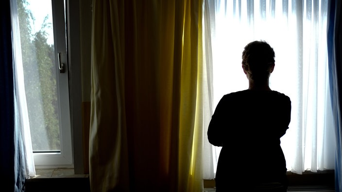 Eine Frau steht am Fenster eines Frauenhauses und schaut nach draussen