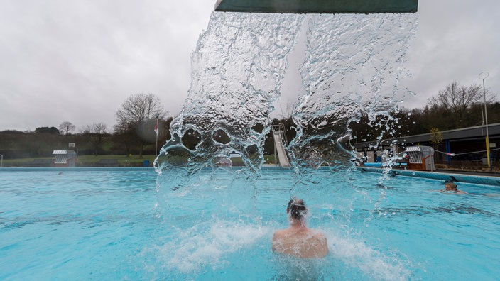 Ein Mann steht im Freibad in Oelde-Stromberg (Nordrhein-Westfalen) unter einer Wasserdusche