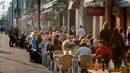 Viele Menschen sitzen in Straßencafes