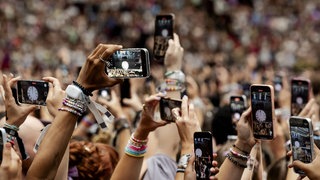 Fans halten ihre Smartphones auf einem Konzert nach oben, um zu filmen.