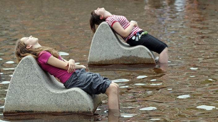 Kinder erfrischen sich in einem Springbrunnen