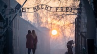 Besucher stehen am frühen Morgen am Tor zum früheren Konzentrationslager Auschwitz mit dem Schriftzug "Arbeit macht frei"